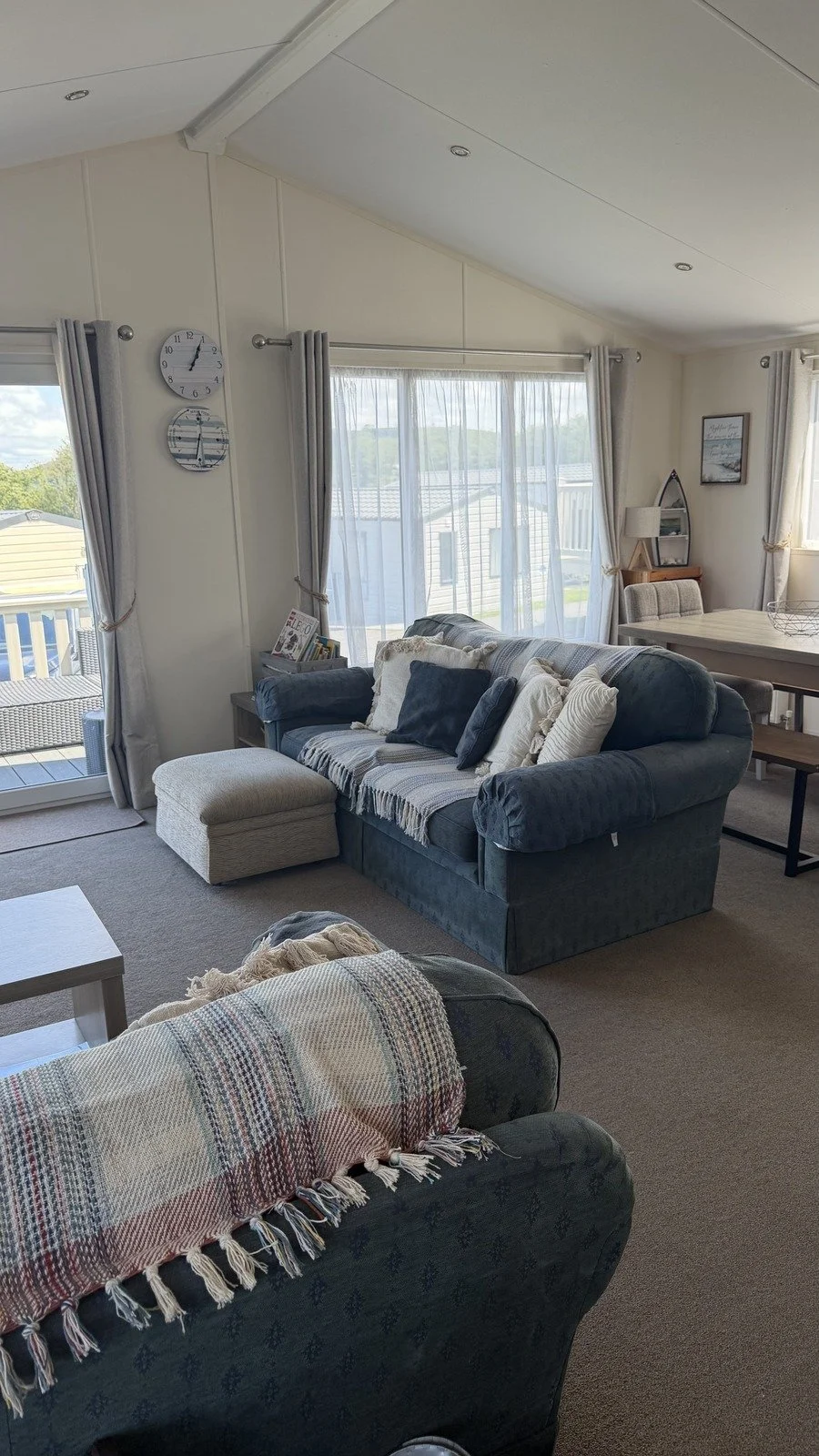 Living room with a blue sofa, an ottoman, a plaid blanket, a fireplace, large windows with sheer curtains, dining table, yellow wall, and wall decor.