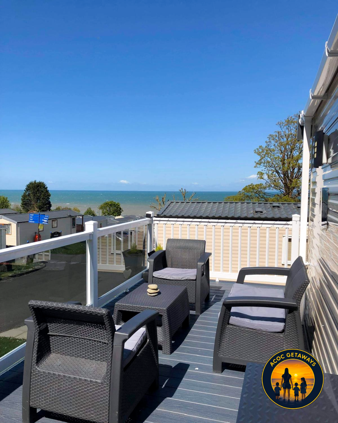 A balcony with outdoor chairs and a small table overlooking the ocean and sky.