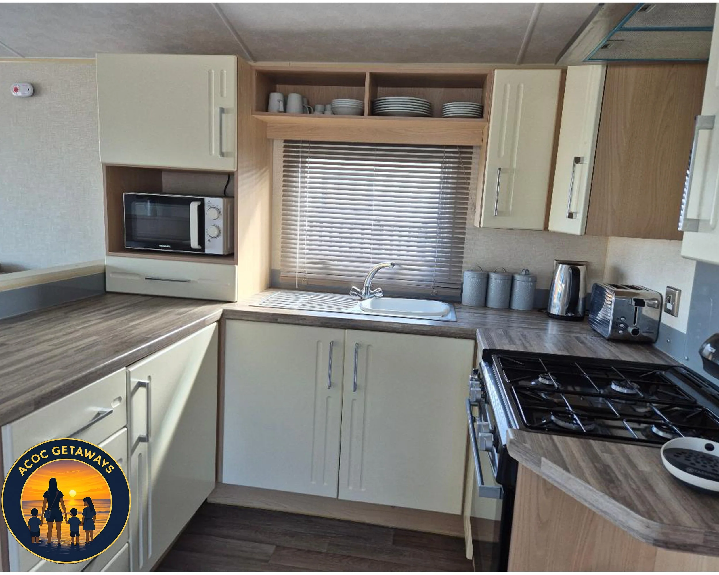 Kitchen with beige cabinets, wood countertops, a window with blinds above the sink, a microwave, toaster, kettle, and organized dishes in open shelves.