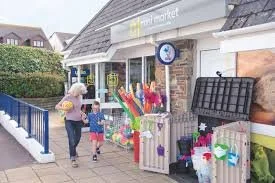 Two women and a child looking at a colorful gift shop display outside.