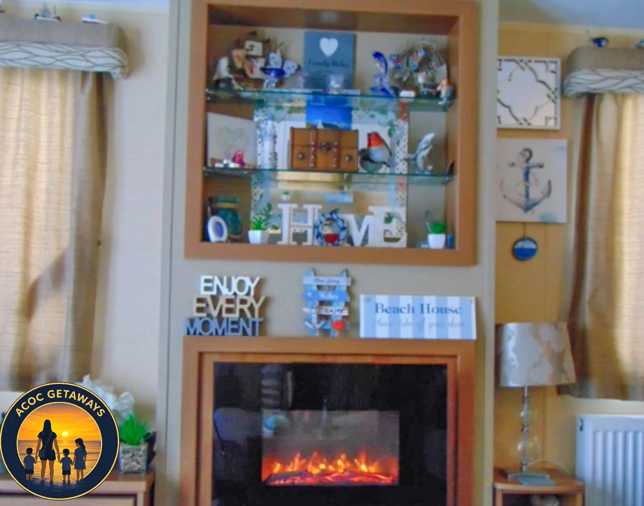 Living room with a fireplace, wooden shelves, and nautical-themed decorations including anchor and boat signs, and a lamp on a side table.