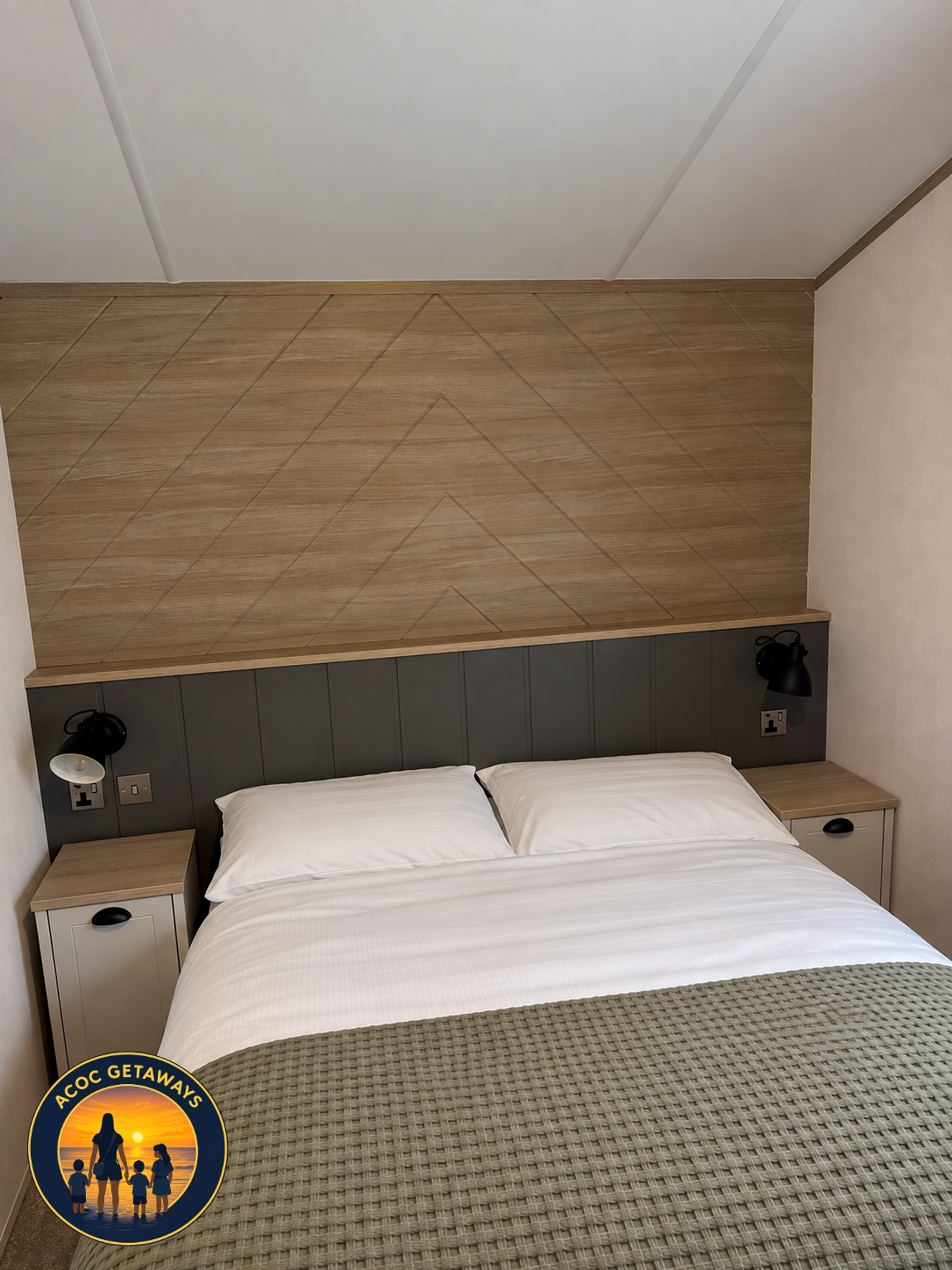 A neatly made bed with white pillows and a beige blanket, flanked by two nightstands with black lamps in a modern bedroom.