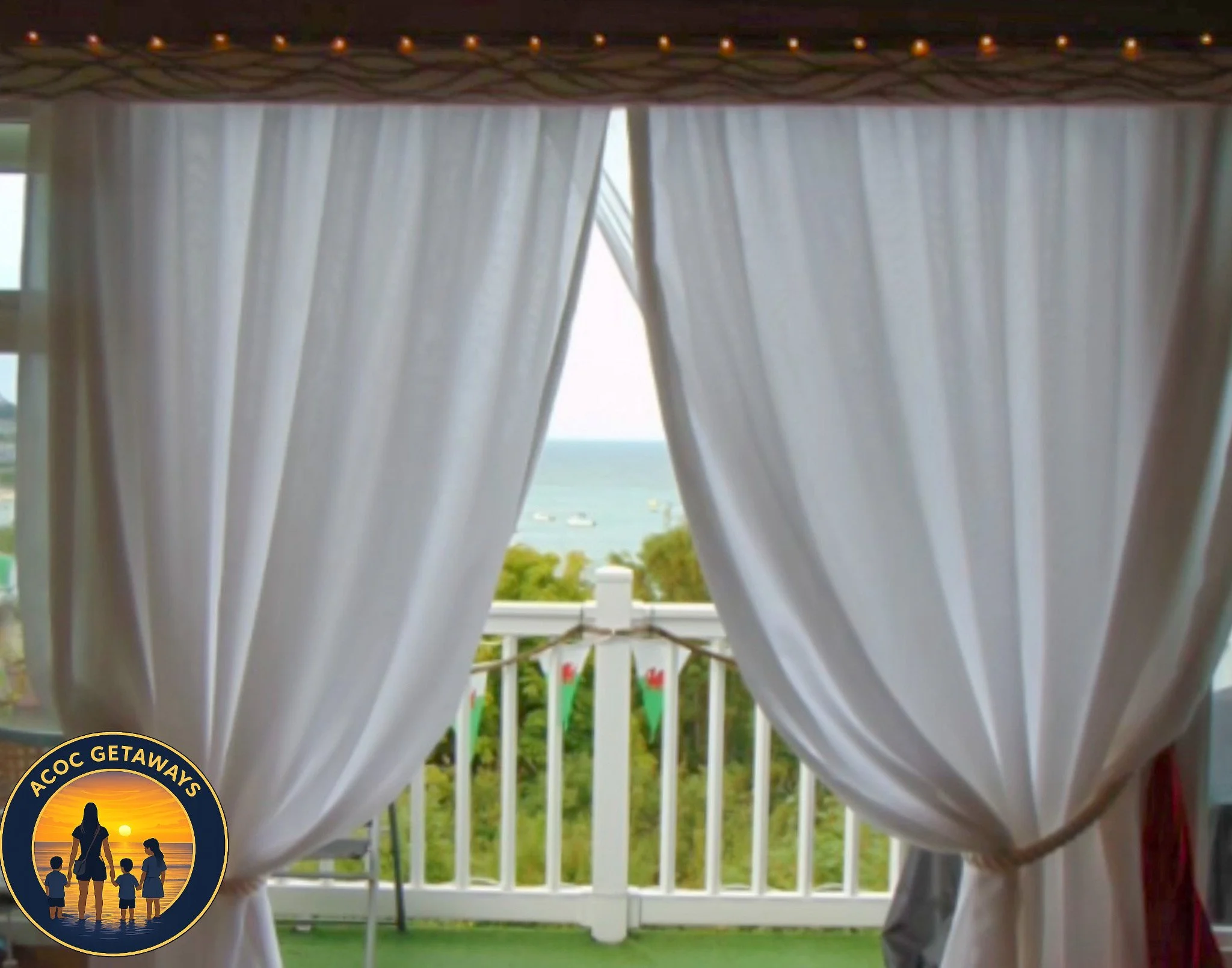 View of an outdoor balcony with white curtains and a railing, overlooking trees, water, and boats on a sunny day.