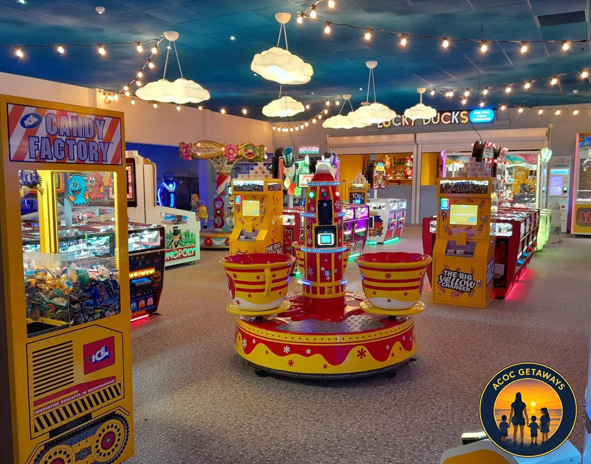 Indoor arcade with various coin-operated games and a bright, colorful atmosphere, decorated with hanging cloud-shaped lights.