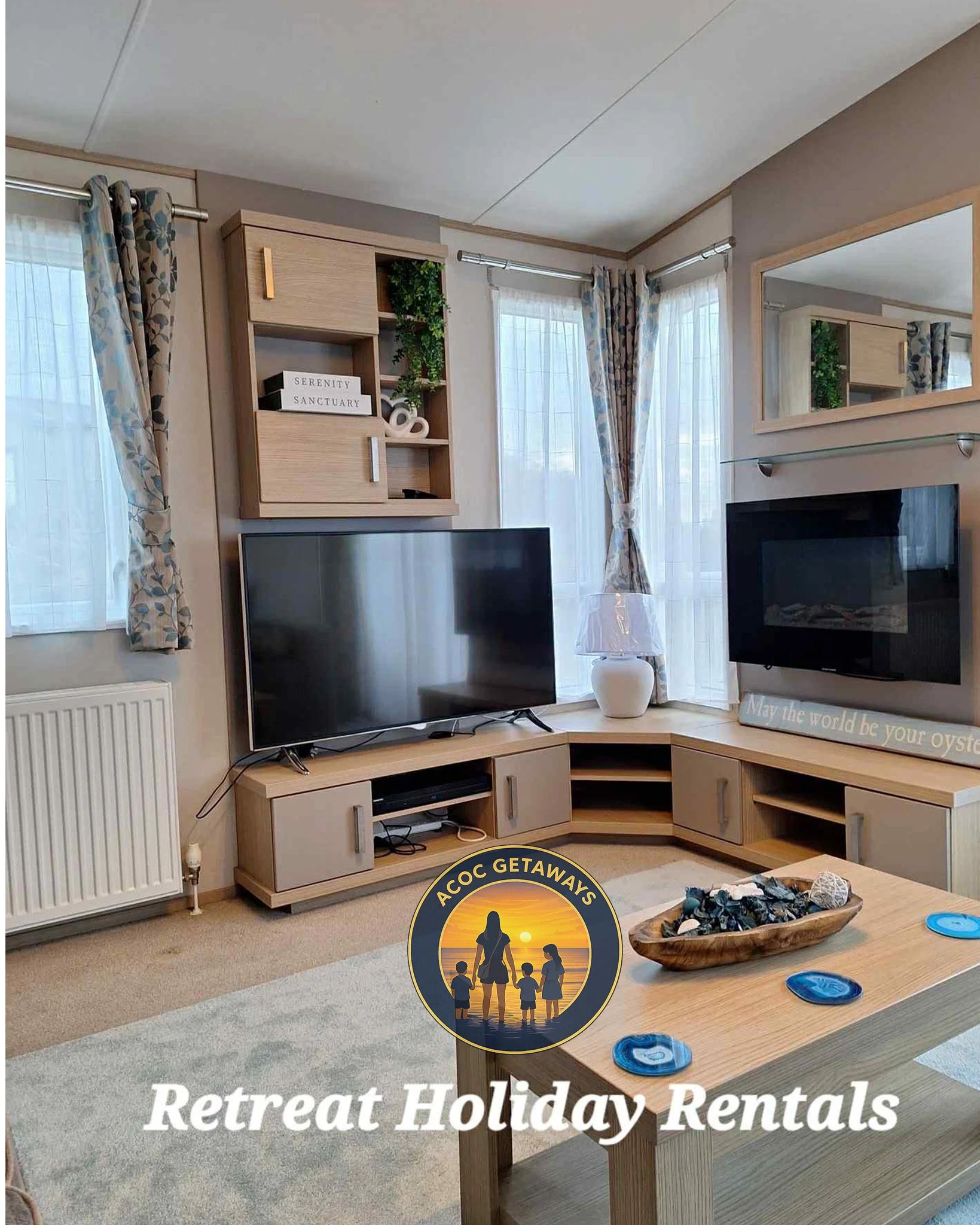 Living room with twin flat-screen TVs, a corner cabinet, decorative curtains, a lamp, and a coffee table with shells and blue coasters, with text overlay 'Retreat Holiday Rentals' and a logo of a family at sunset.