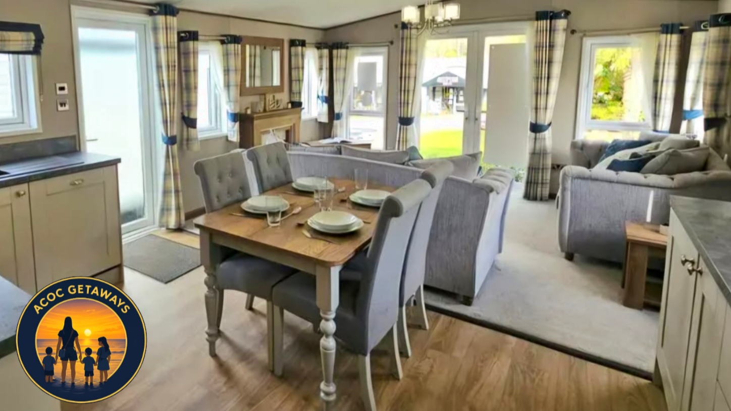 A cozy living and dining area with a wooden dining table set for four, surrounded by upholstered chairs, and a living space with multiple sofas and armchairs arranged around a window and glass door leading outside. The room features large windows with plaid curtains and hardwood flooring.