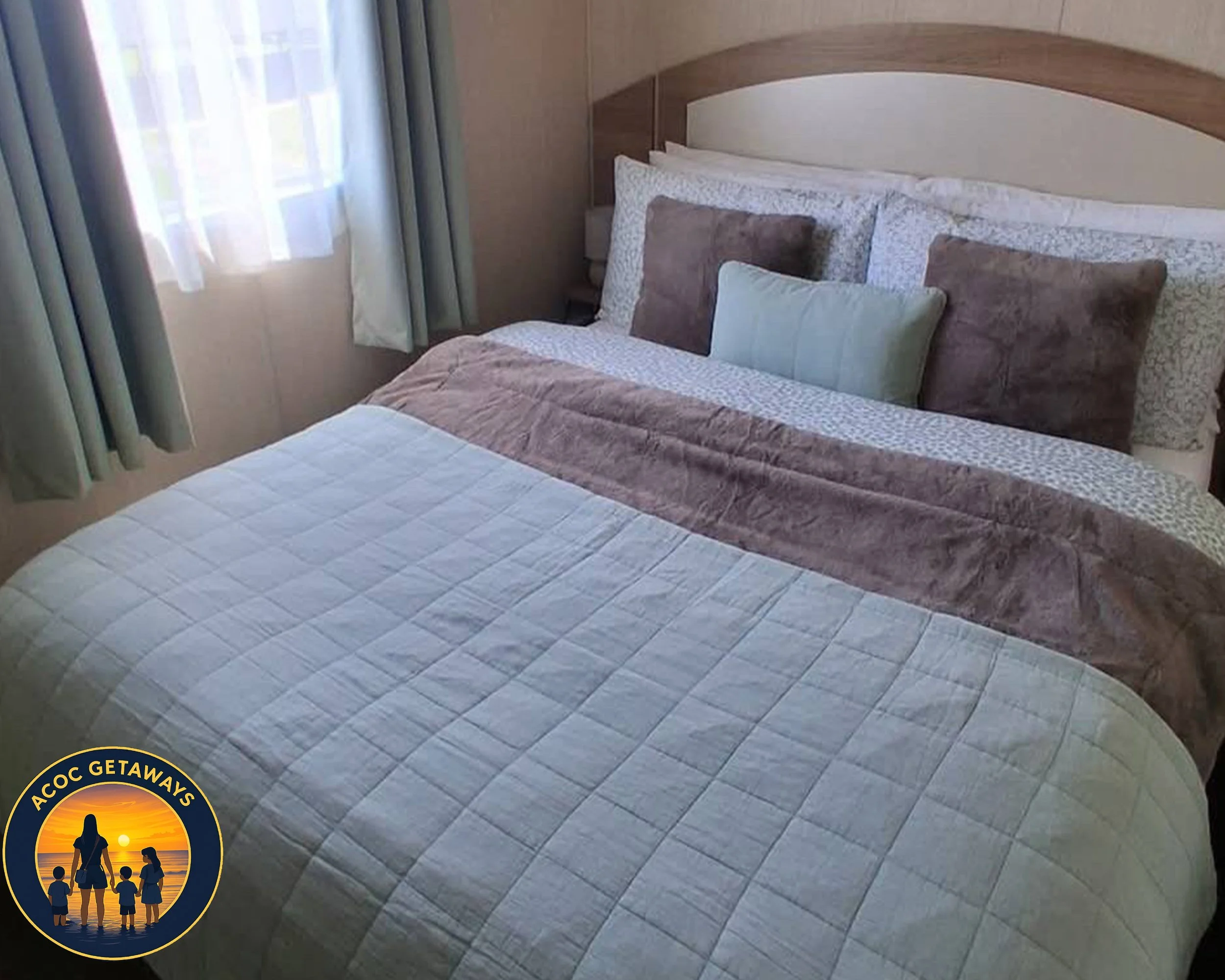 A neatly made bed with multiple pillows in a hotel room, next to a window with curtains.