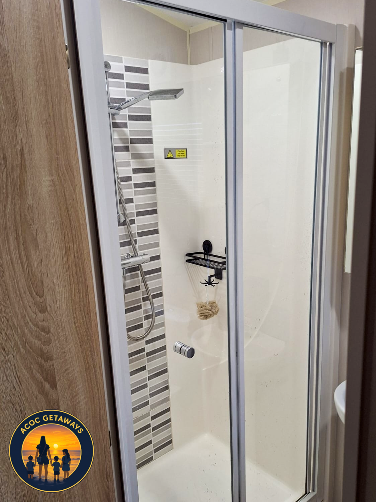Shower stall with a sliding glass door, showerhead, and wall-mounted shelf in a bathroom.