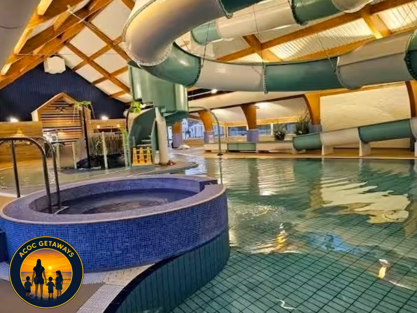 Indoor water park with a large water slide, a hot tub, and a swimming pool, featuring wood and green accents and a high, curved ceiling.
