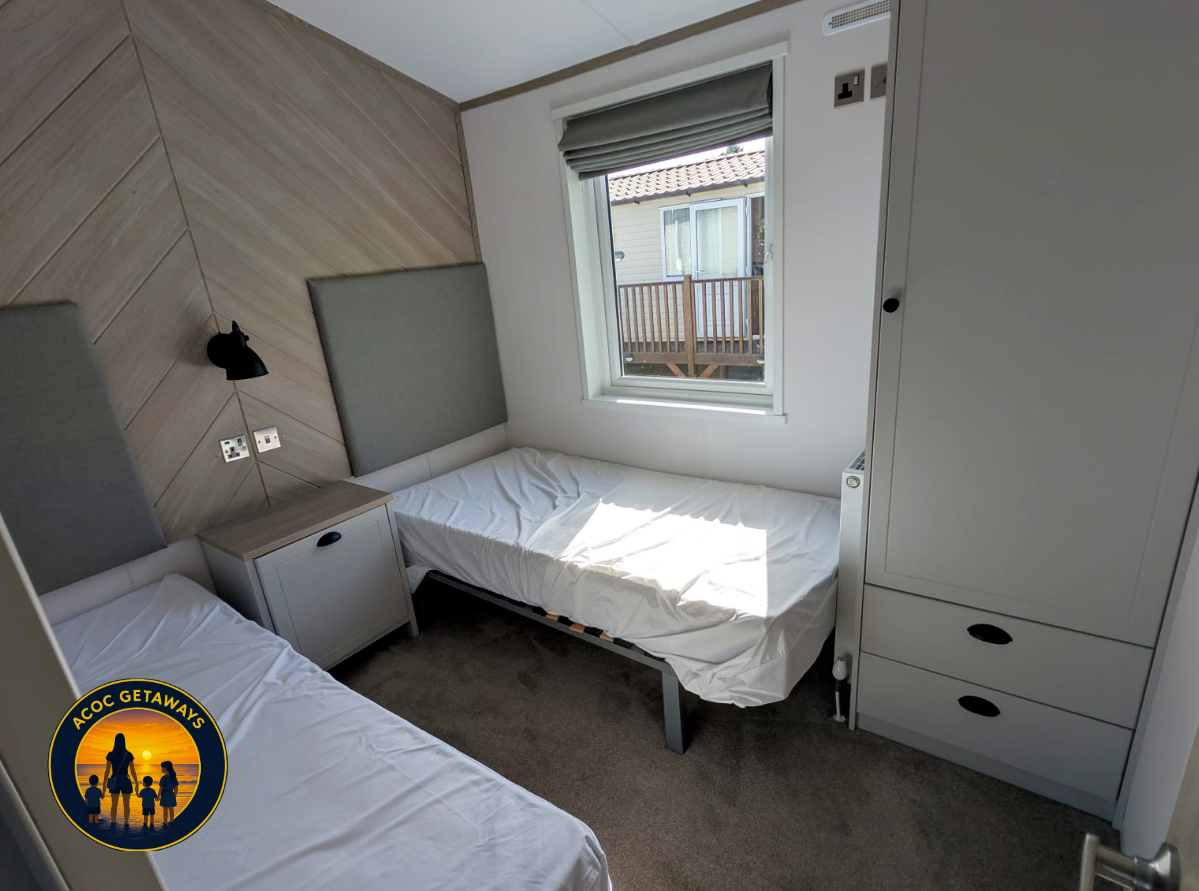 Bedroom with two beds, a window, a bedside table, and a large wardrobe.