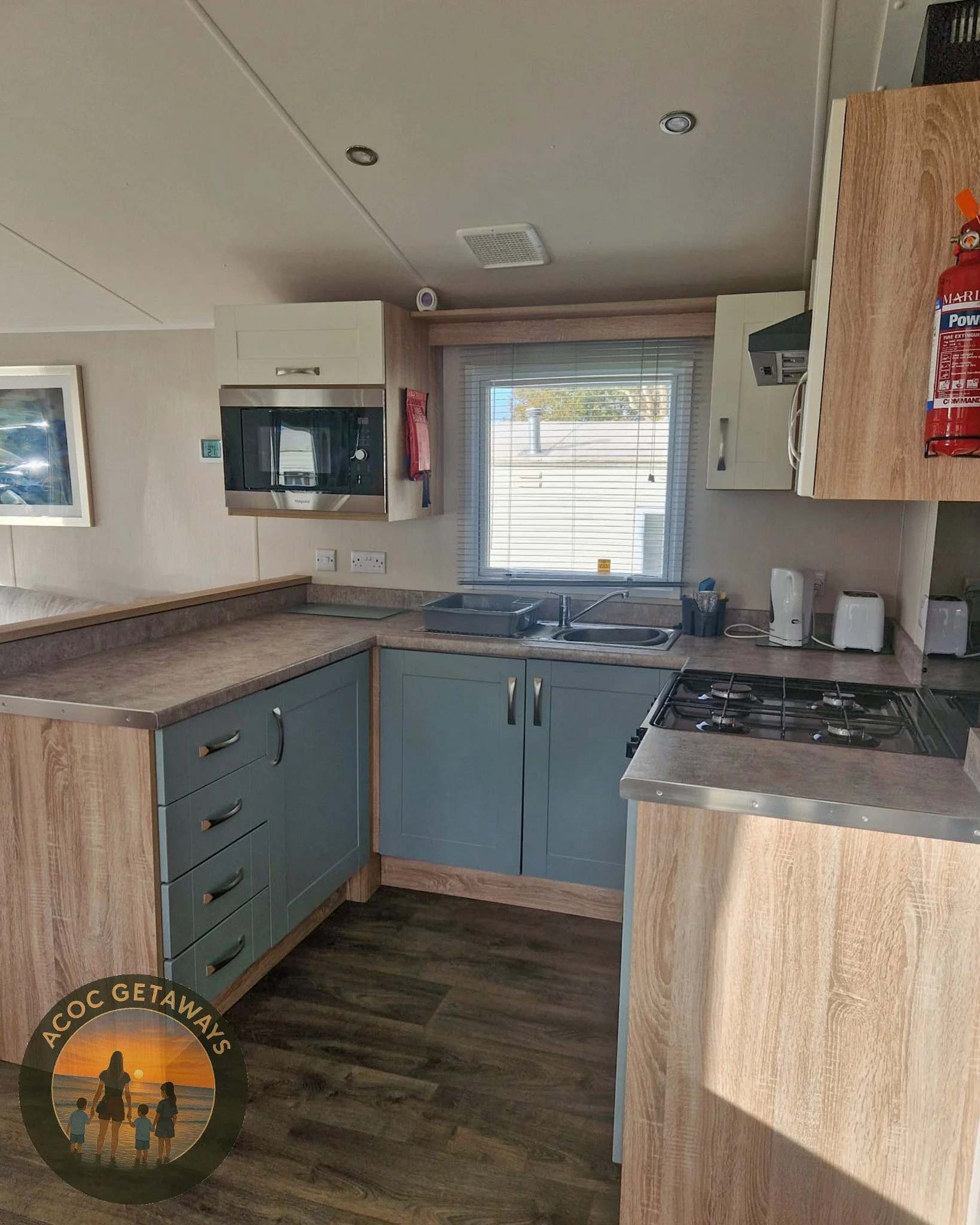 Kitchen with blue cabinets, a window, a microwave, a sink, and small appliances on the counter.