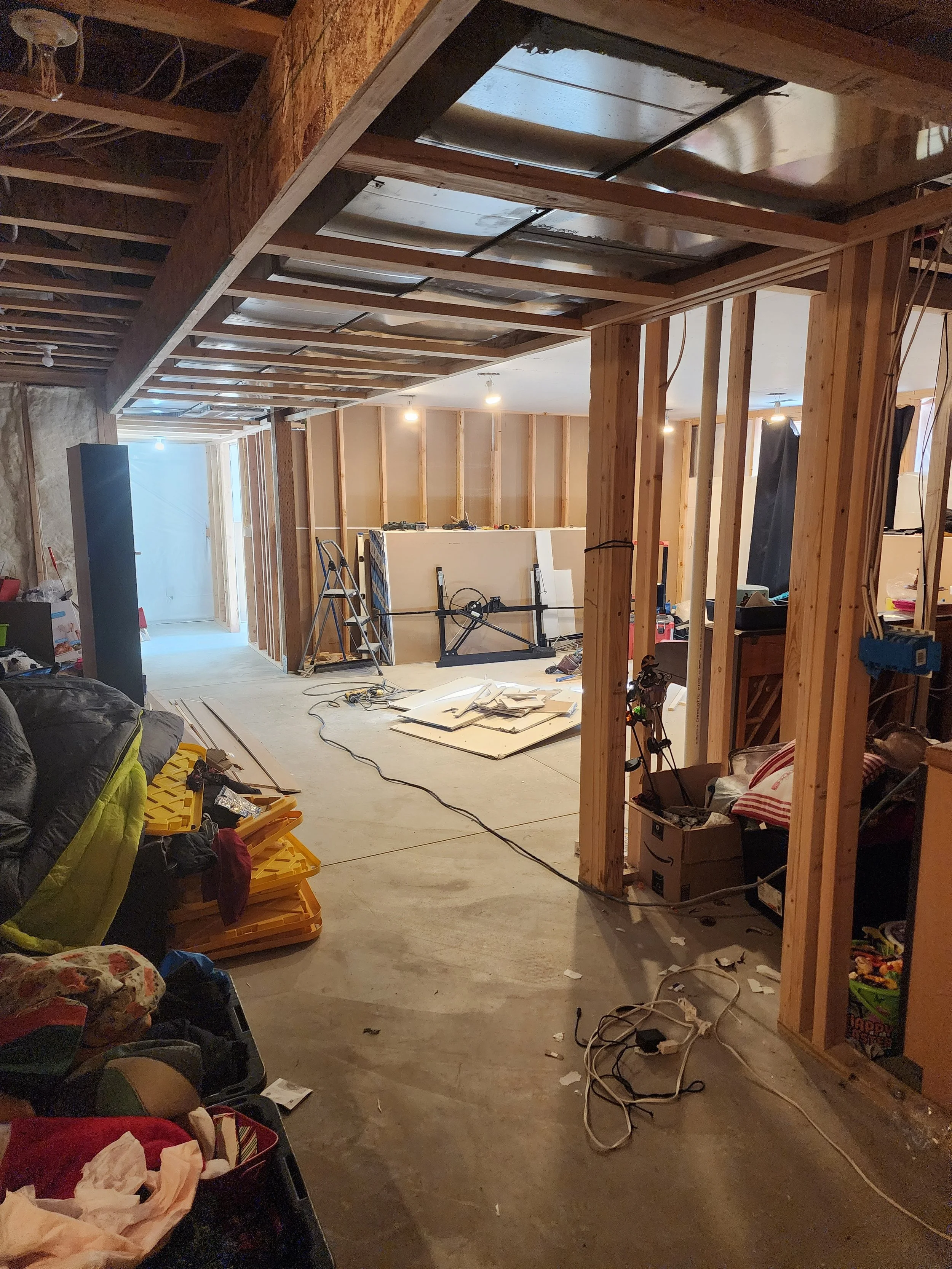 Construction site with exposed wooden framing, unfinished walls, scattered tools, and materials for building or renovating a space.
