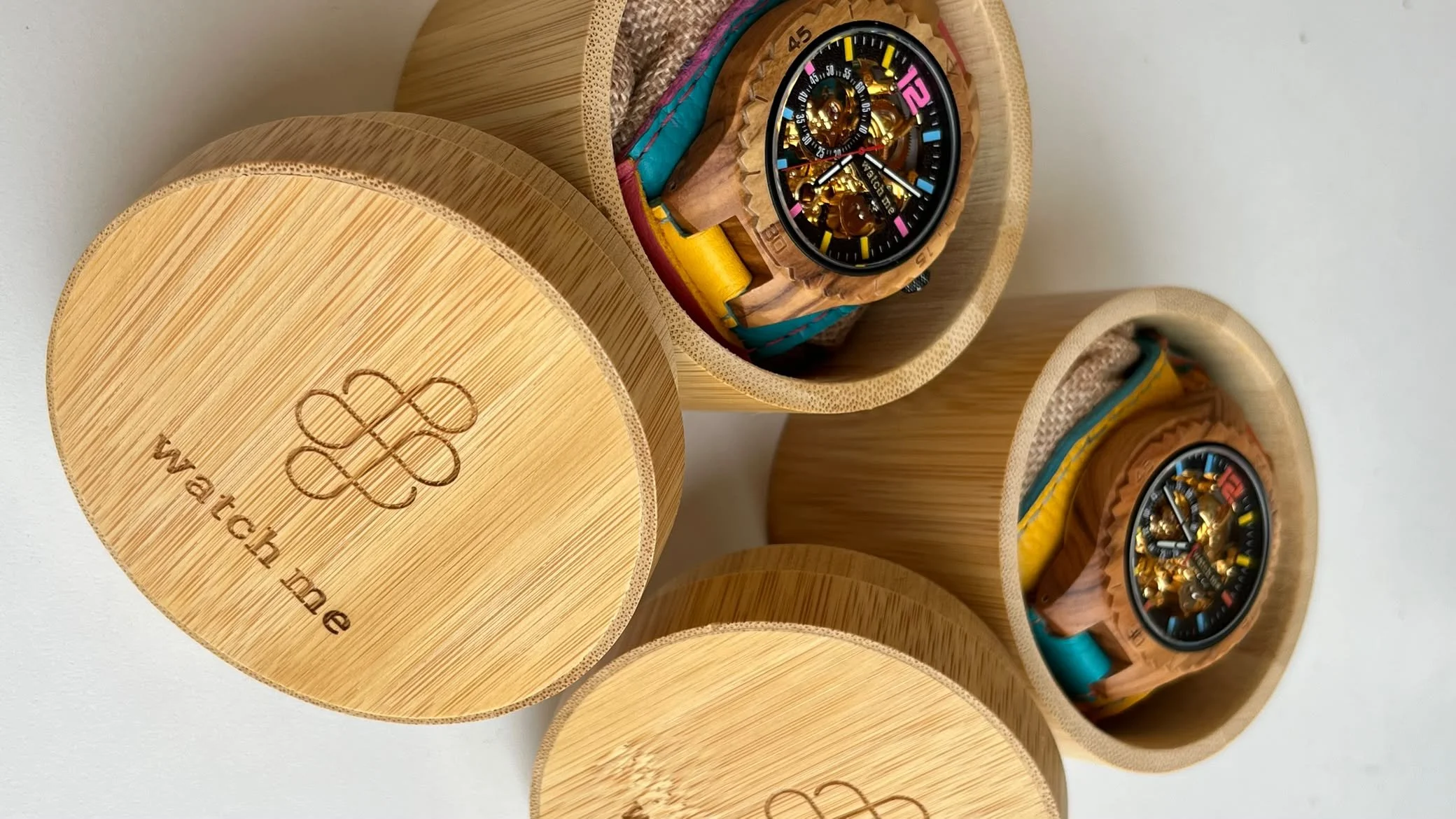 Montres Swatch en bois dans des boîtes cylindriques en bois avec le logo Swatch et le site web swatch.com.