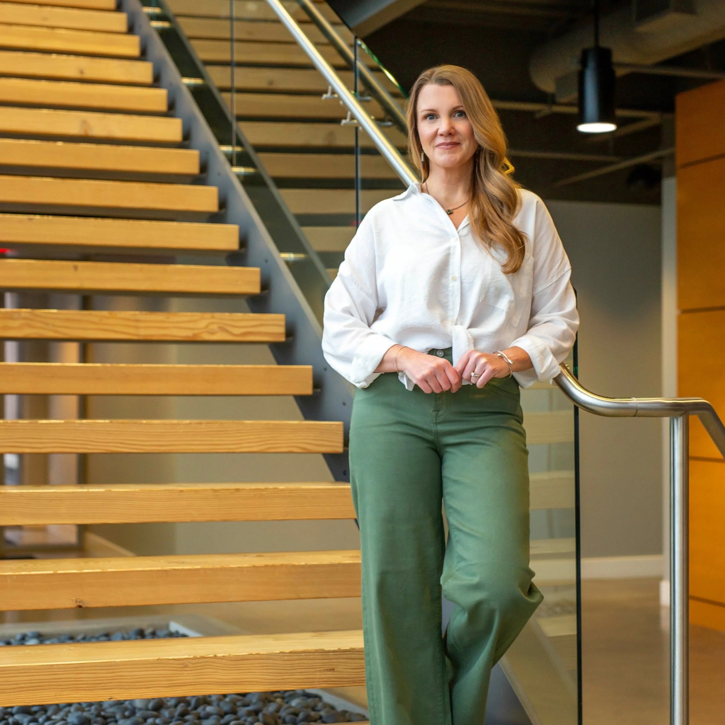 Stacey Sloan RDH M.Ed standing on modern wooden staircase, HygieneLEAD dental leadership founder