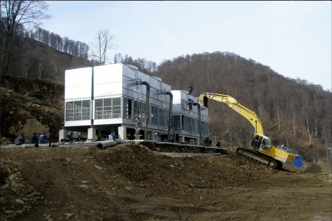 Construction site with workers installing snowmaking cooling towers.