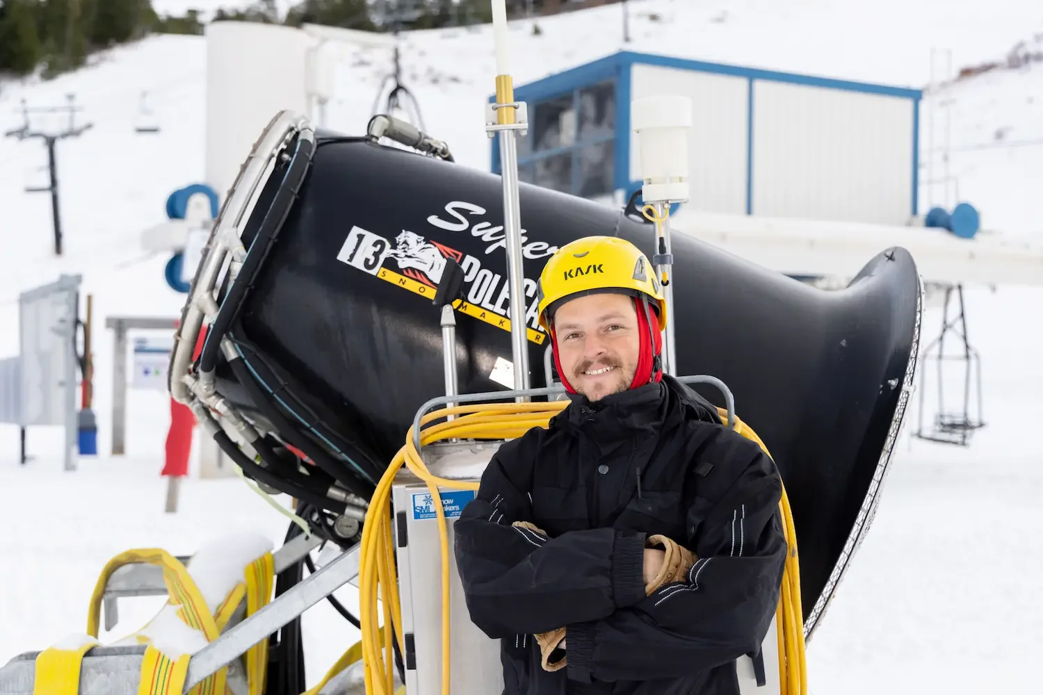 BogusBasinSnowMakerSmilesInFrontOfSnowMakingMachineOnTheSnow_Fall2022_PhotoByLukeTokunaga_2048px1366px copy.webp
