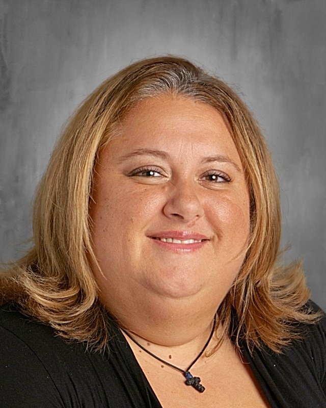 Portrait of a woman with shoulder-length blond hair, smiling, wearing a black top and a necklace
