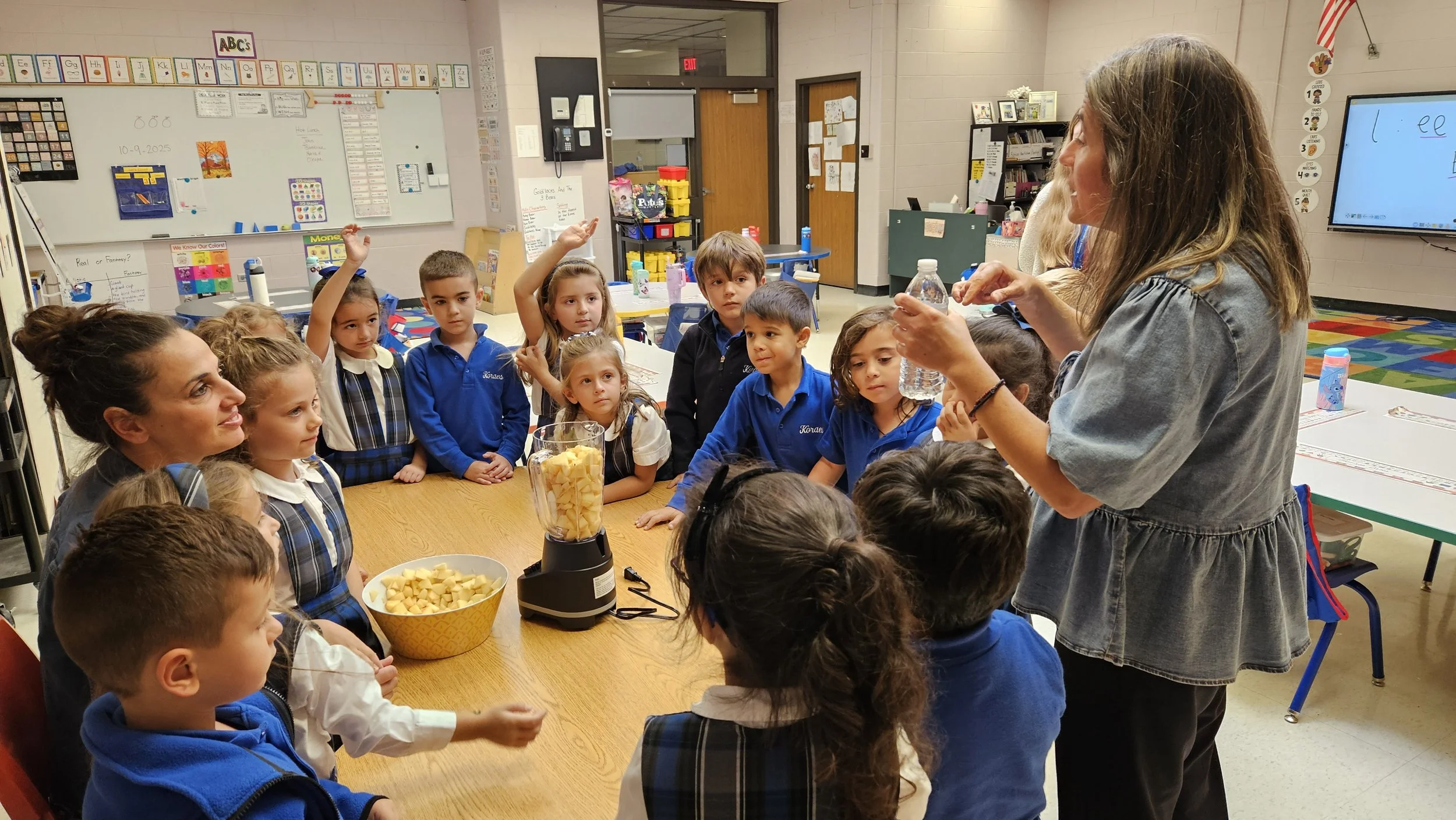 A teacher demonstrating a water bottle to a group of elementary school students in a classroom.
