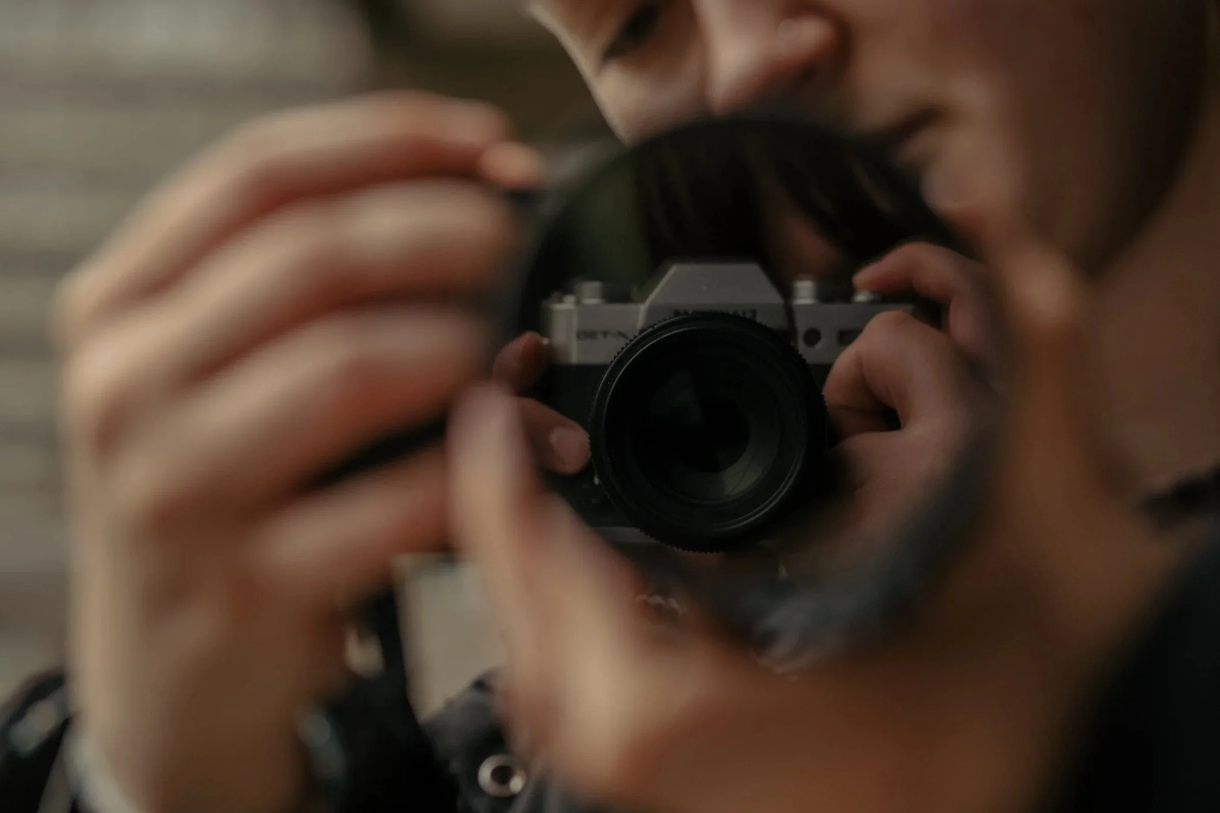 Person taking a photo with a camera, seen through a mirror reflection