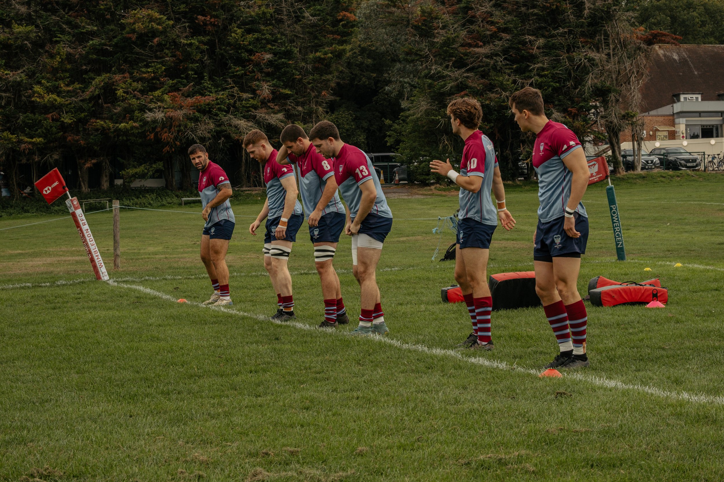 Rugby players in maroon and blue uniforms preparing for a match on a grassy field.