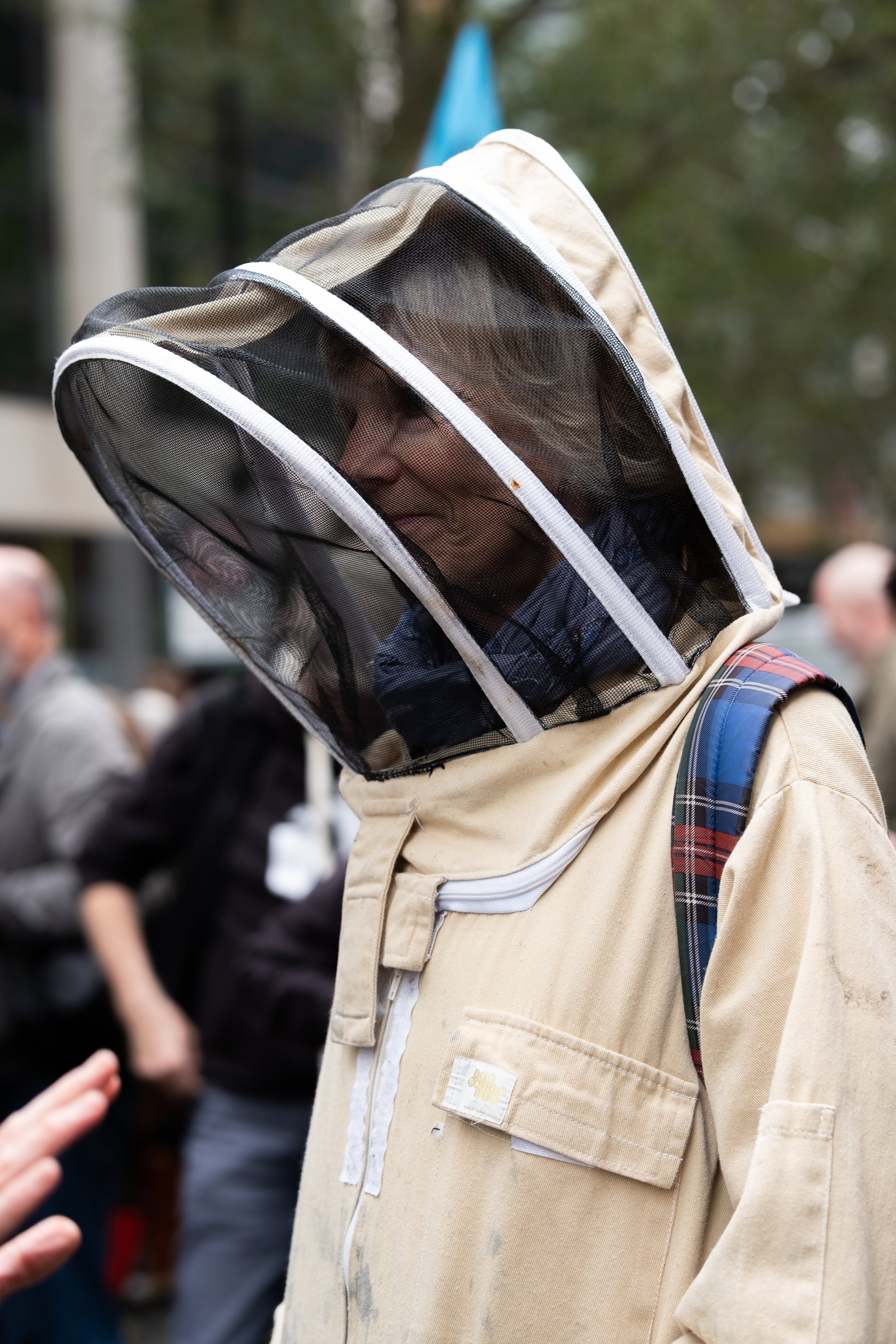 A person wearing a beekeeper suit and veil at an outdoor event.