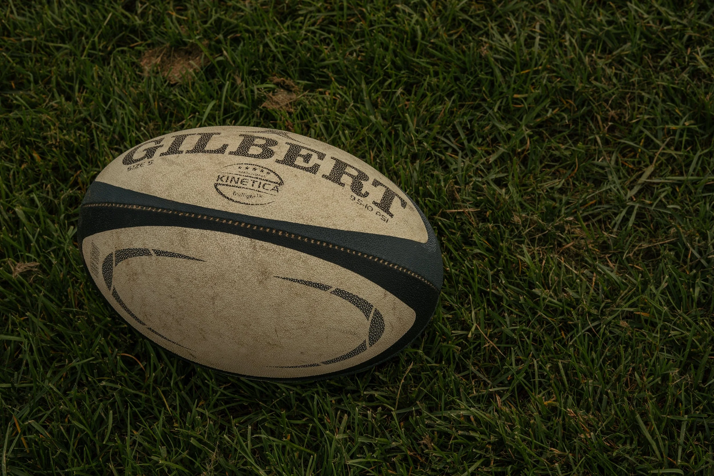 A rugby ball resting on green grass.