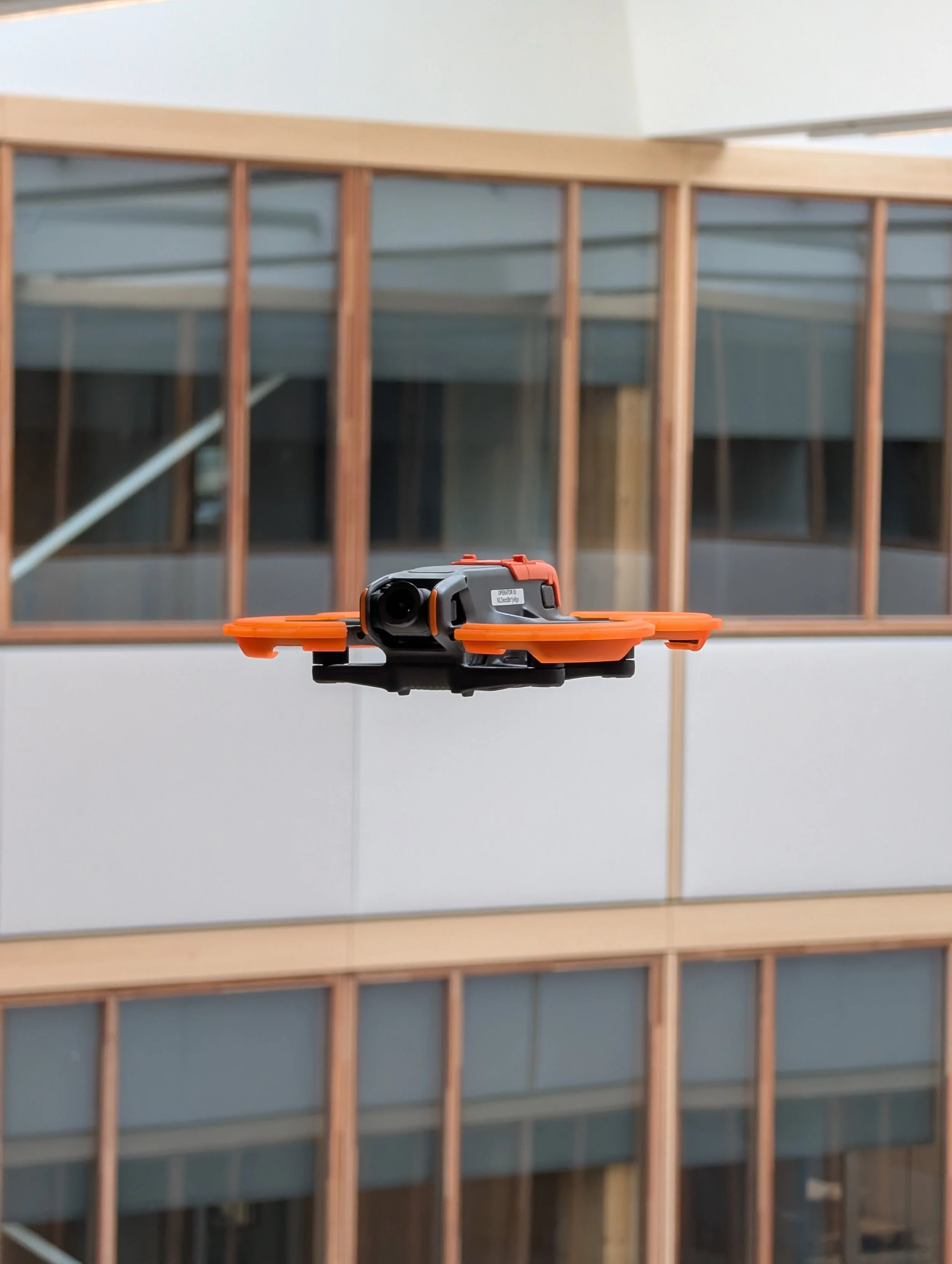 A construction site with a wooden framed wall, viewed through a window, and an fpv drone in the foreground.