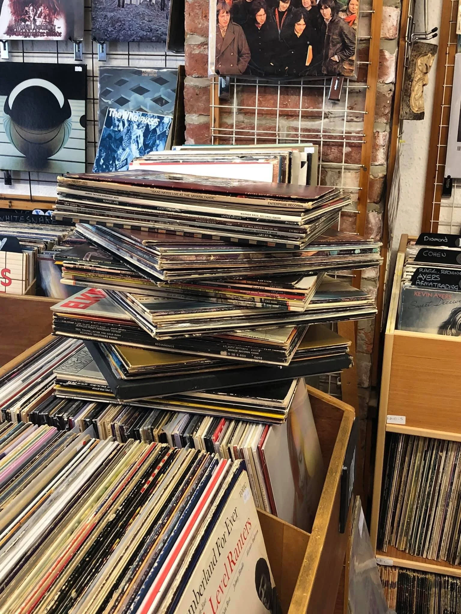 Interior of Music in the Green's Bakewell shop, with a display of stacked vinyl records. There are CDs on the racks and gig posters on the ceiling - the interior has a traditional record shop feel.