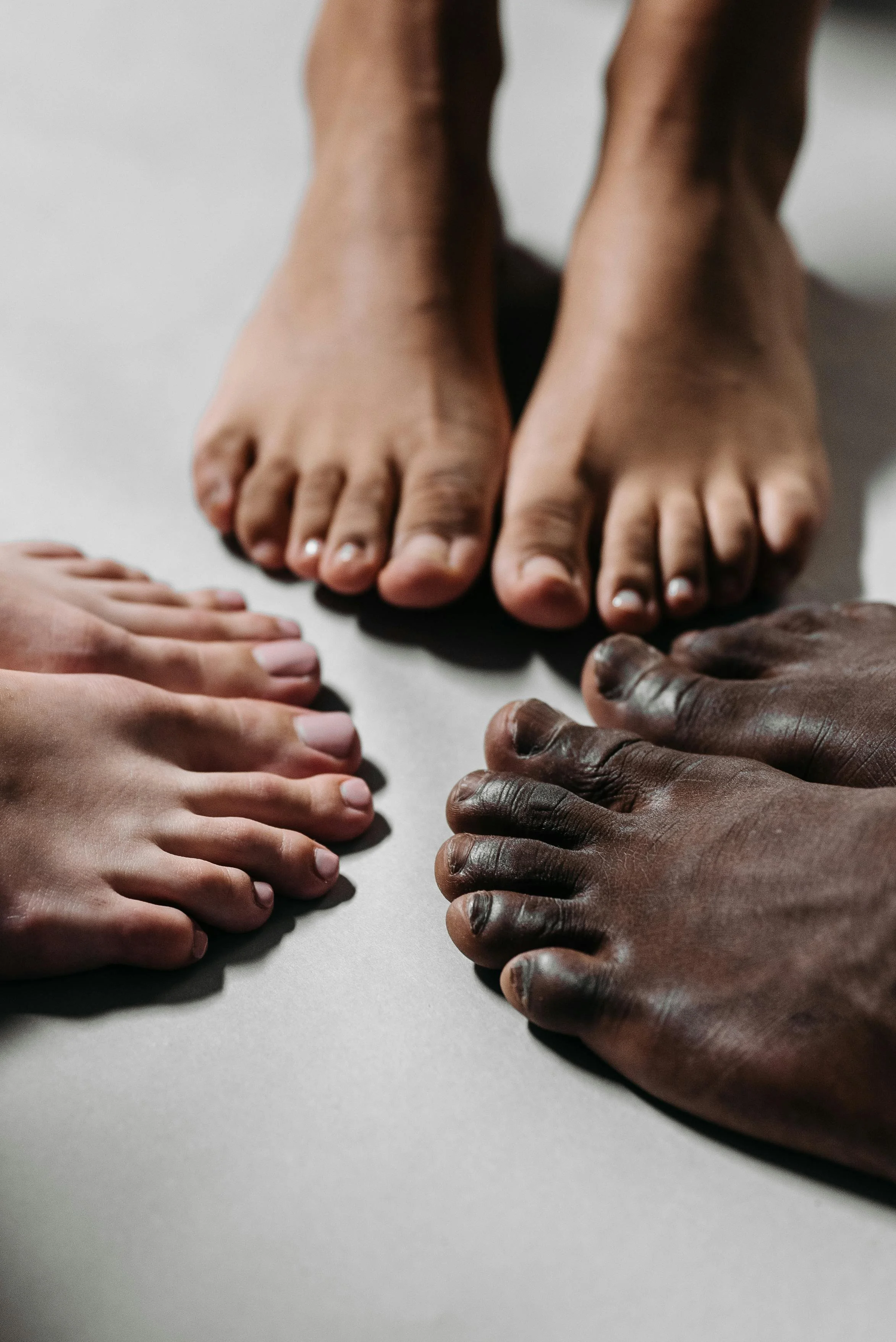 Multiple hands and feet of diverse individuals placed on a flat surface in a circle formation.