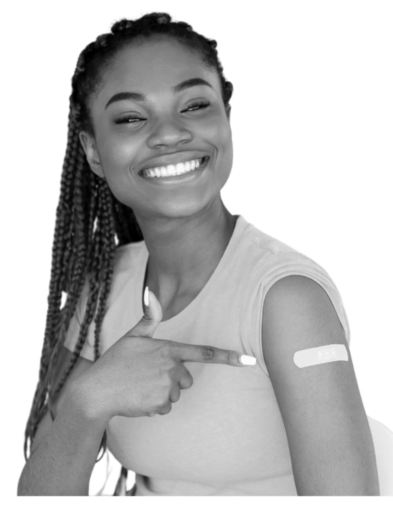 A young woman smiles and points to a band-aid on her left arm.