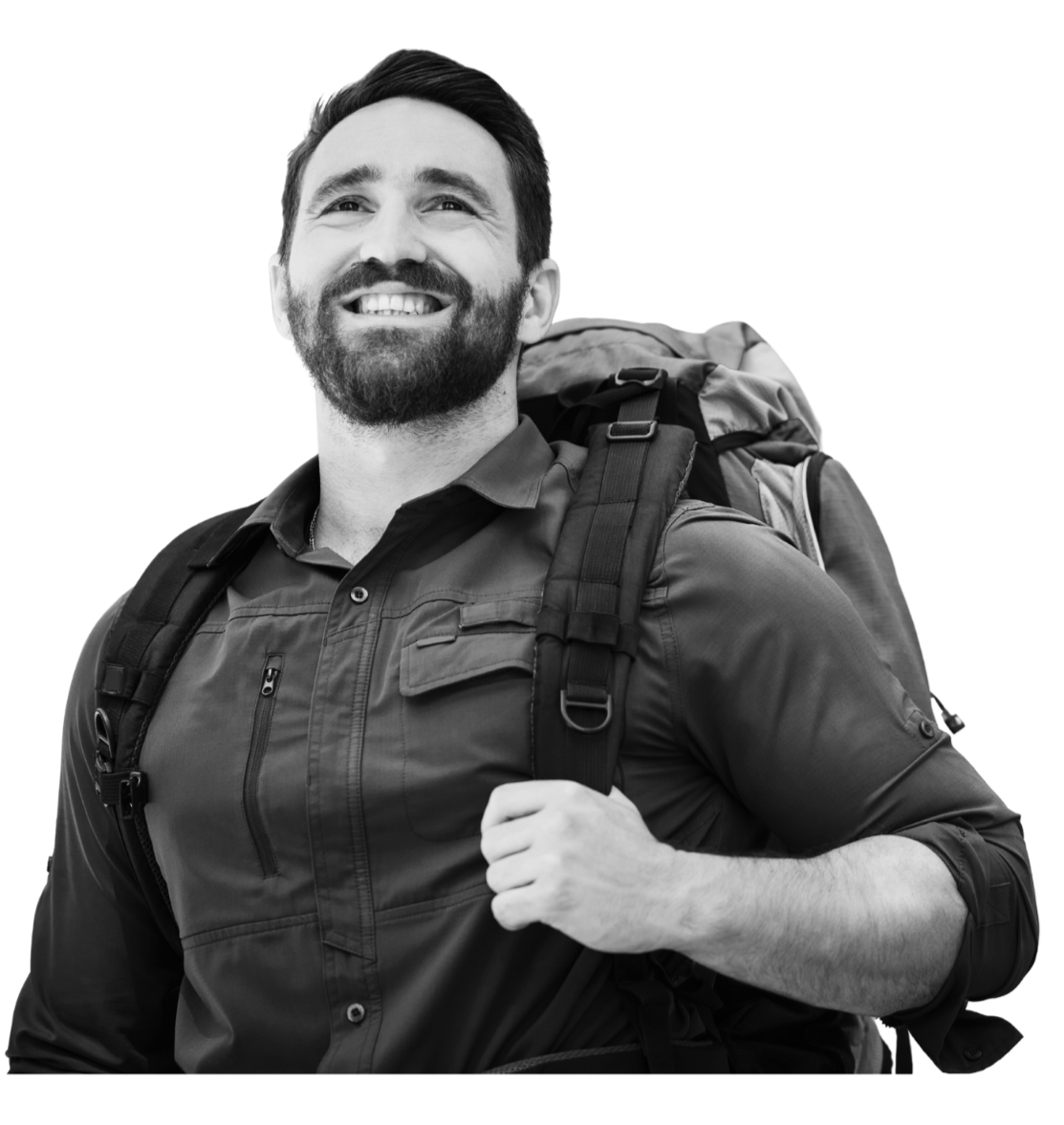 A white male traveller in his 30's with a beard, and a backpack on his back smiles at the camera.