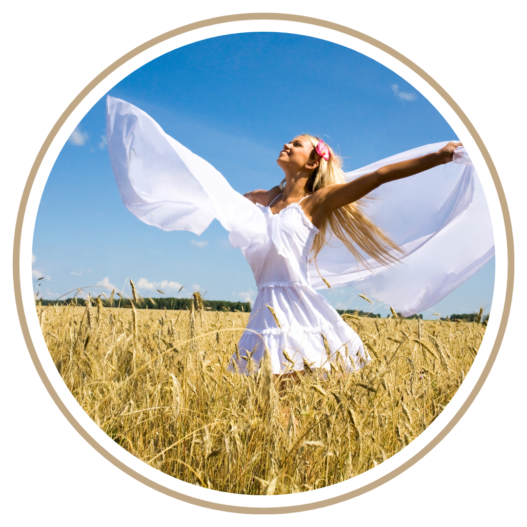 Young woman in white dress with arms outstretched in a wheat field under a blue sky