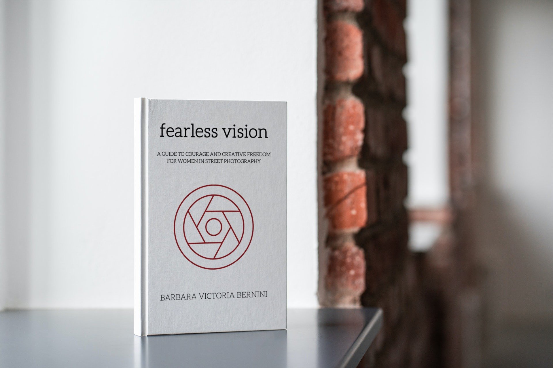 A book titled "Fearless Vision" standing on a white surface with a brick wall in the background.