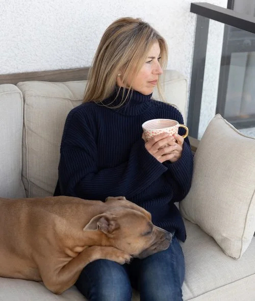 Carolyn Mahboubi, life and leadership coach, reflecting peacefully on a couch with her dog.