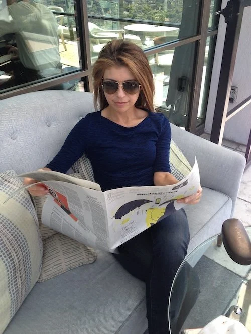Woman relaxing in a cozy armchair reading a newspaper as part of her morning practice
