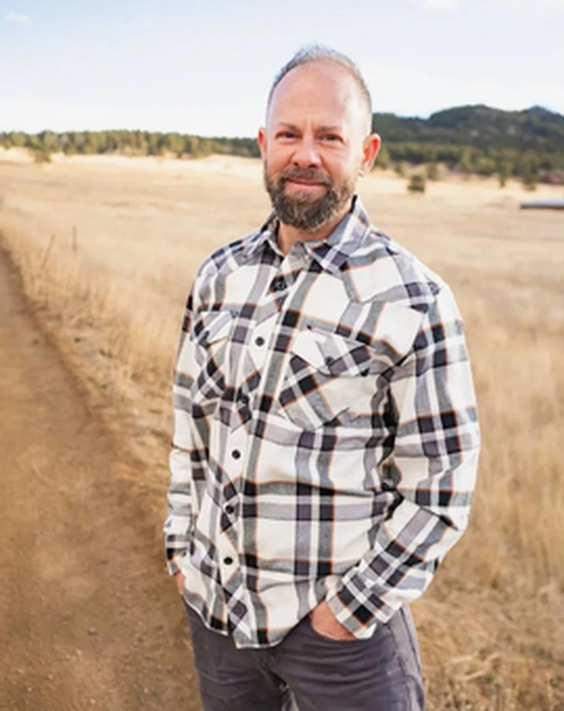 Shane Young, founder of Boulder Canyon Retreat Center, standing on a dry grass trail