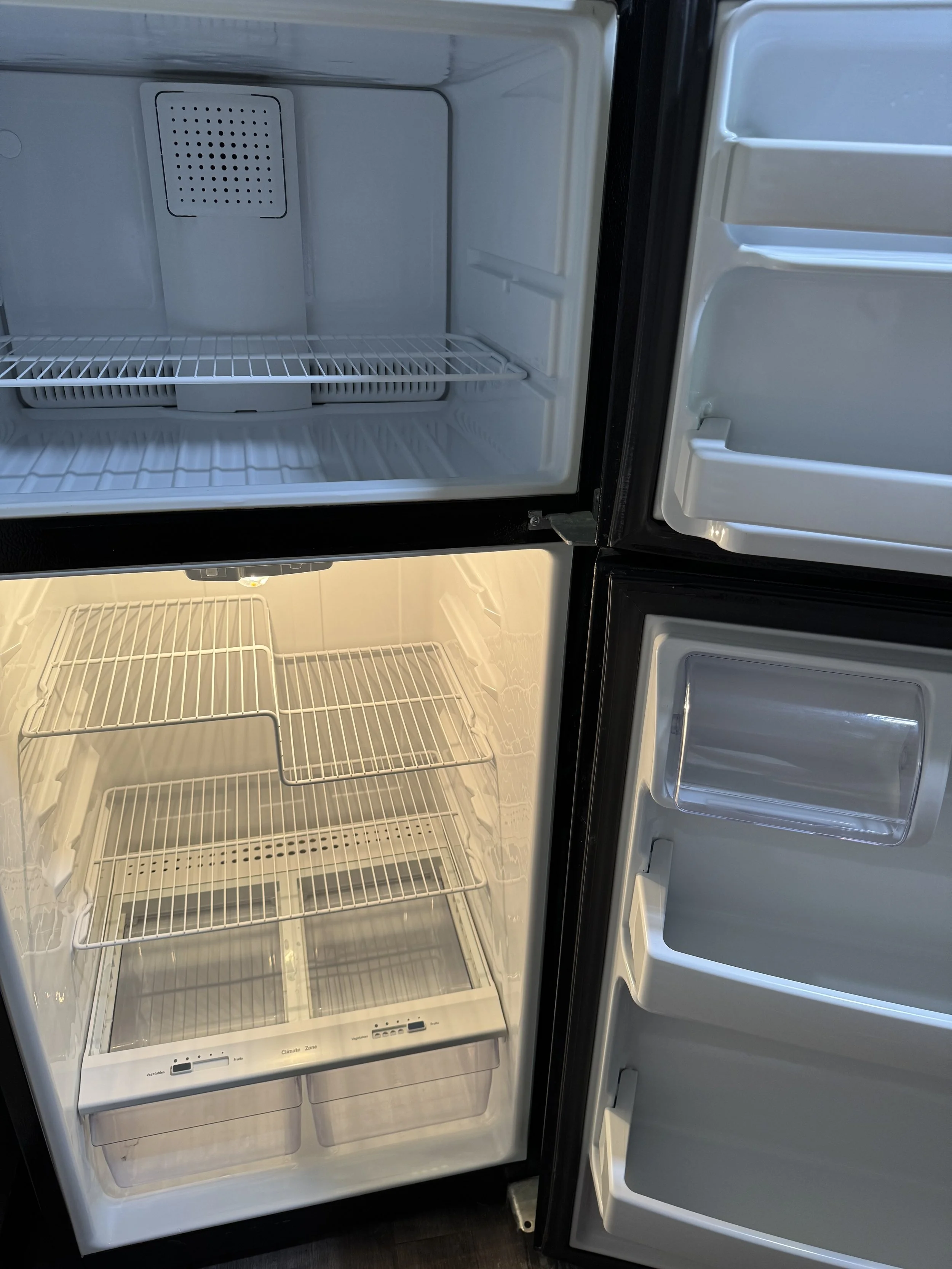 Open refrigerator with empty freezer and fridge sections.