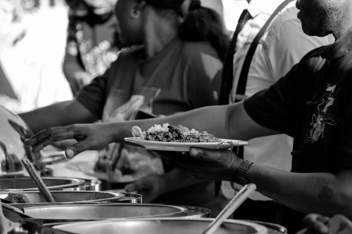 A bunch of people taking food at a catering event