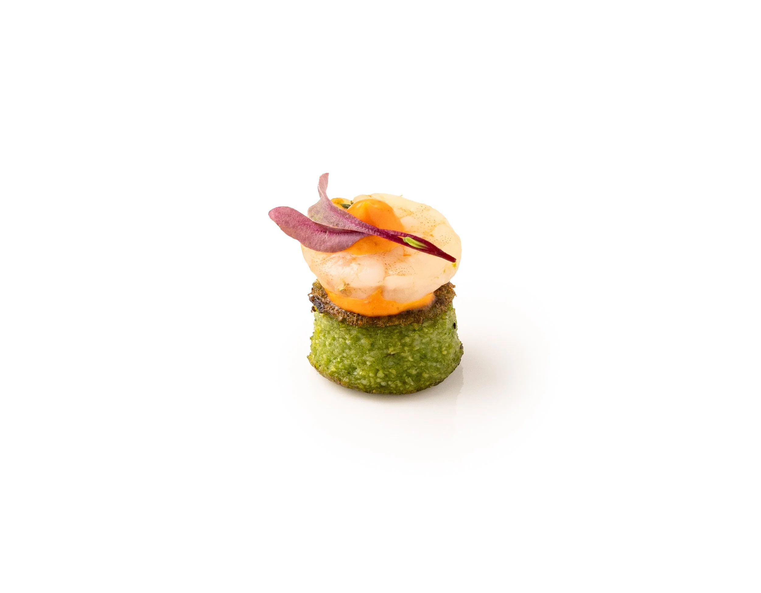 Gourmet appetizer with green base, topped with a poached egg, edible flower, and microgreens, on a white background.
