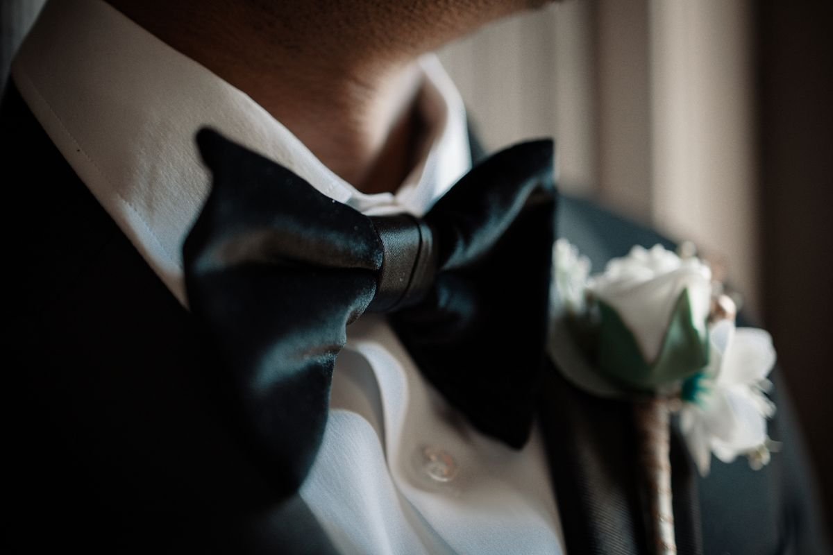 A man wearing a black suit with a bow tie