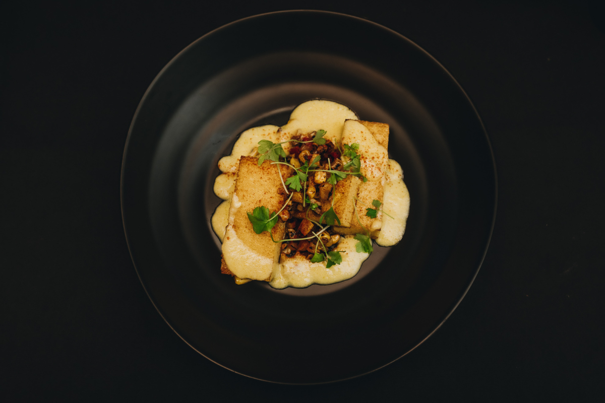 Some food sitting on a black plate against a black background