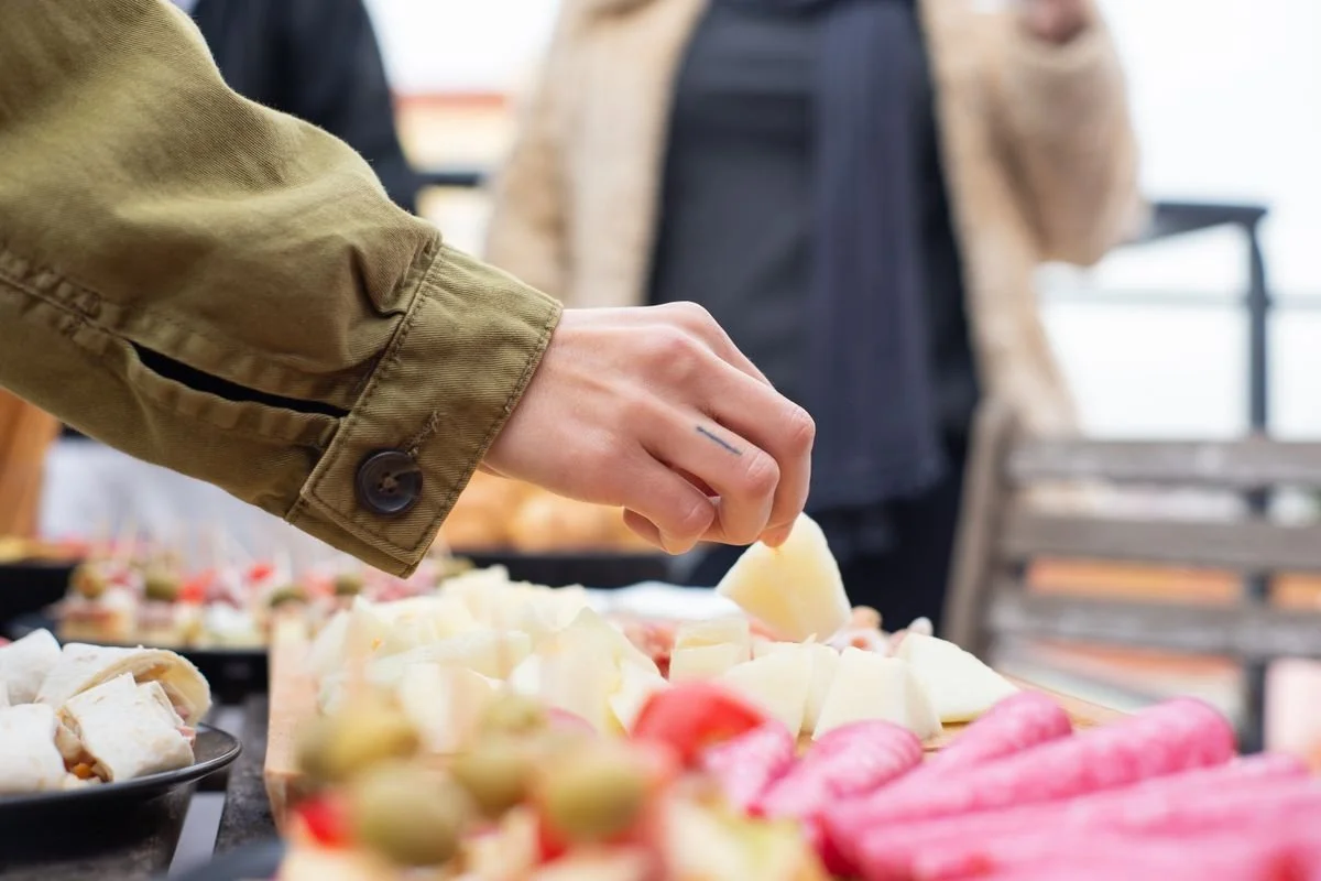 A person grabbing some cheese from a table