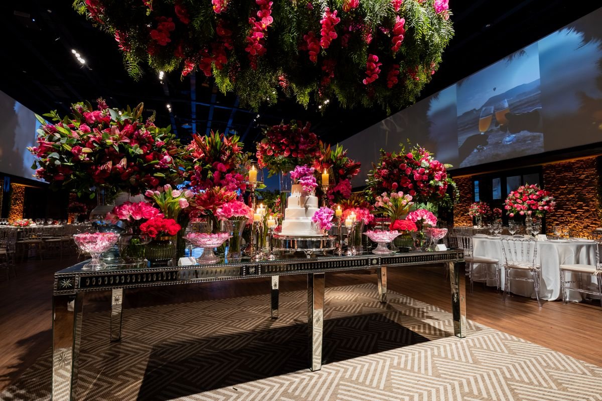 A wedding cake and flowers all on a table at a venue