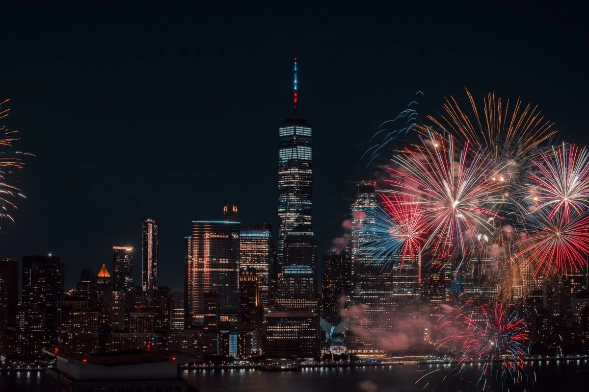 New York City at night with fireworks going off over the water