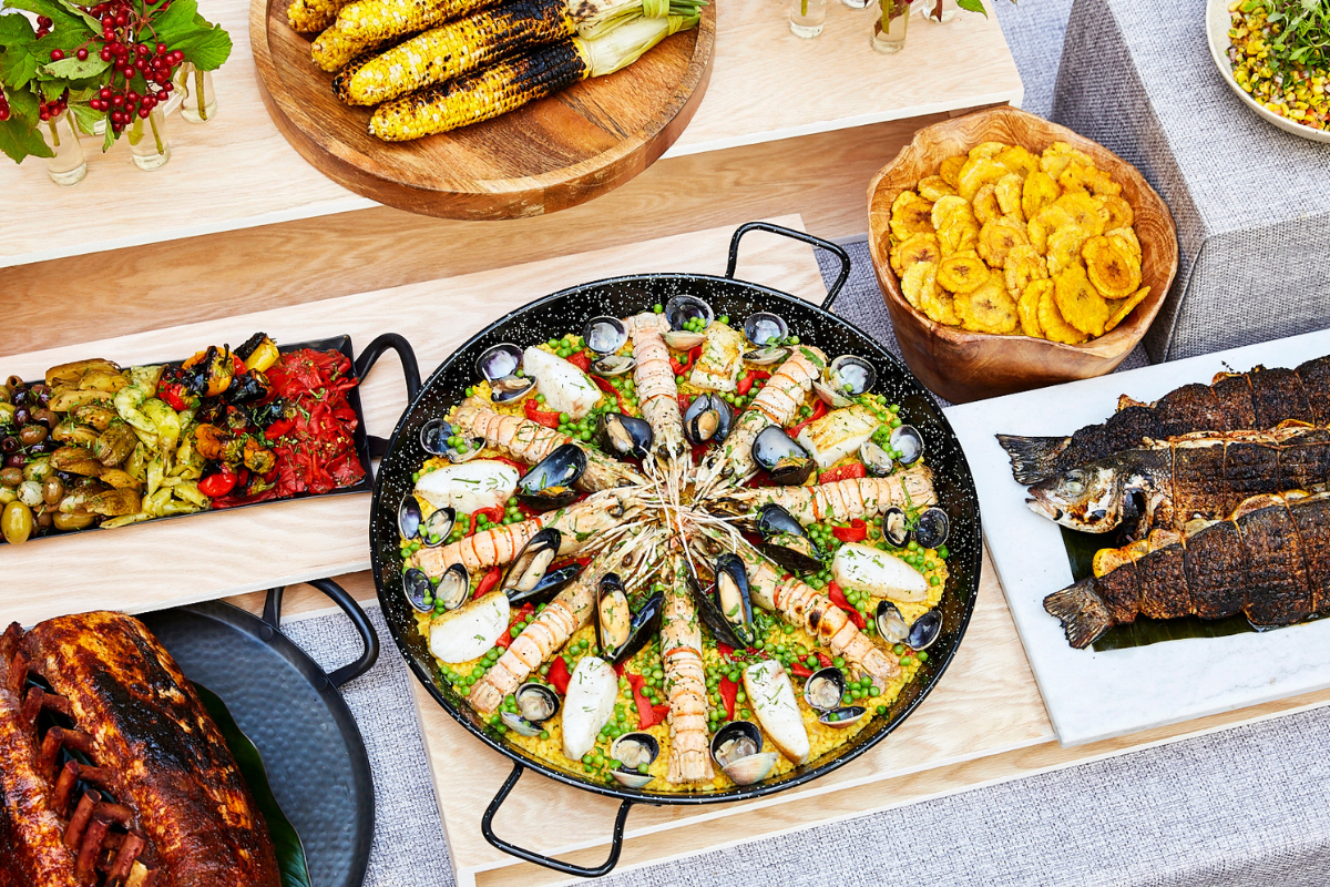 A skillet full of seafood surrounded by a bunch of meats and vegetables