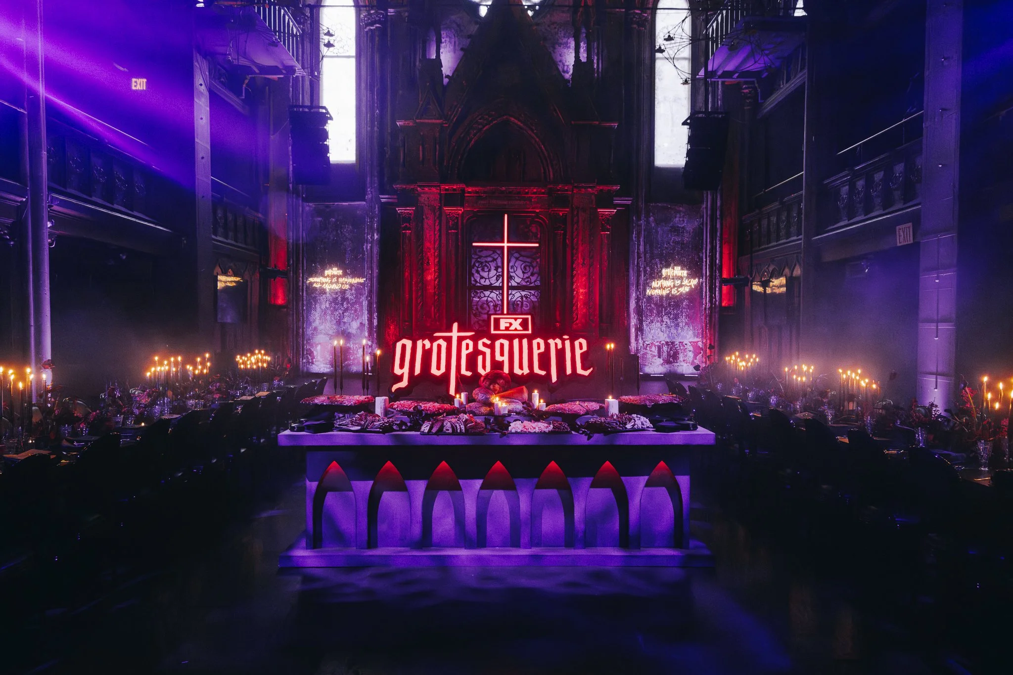 A gothic-themed event setup with a religious motif, featuring candles, flowers, and a neon sign reading 'FX Grotesquerie' in a church-like interior with dark lighting and purple hues.