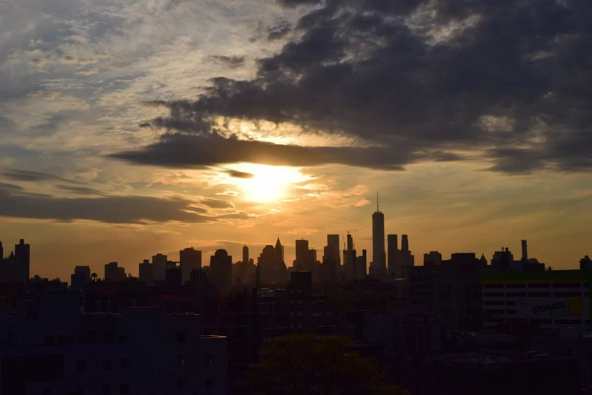 A sunset in New York City with clouds in the sky