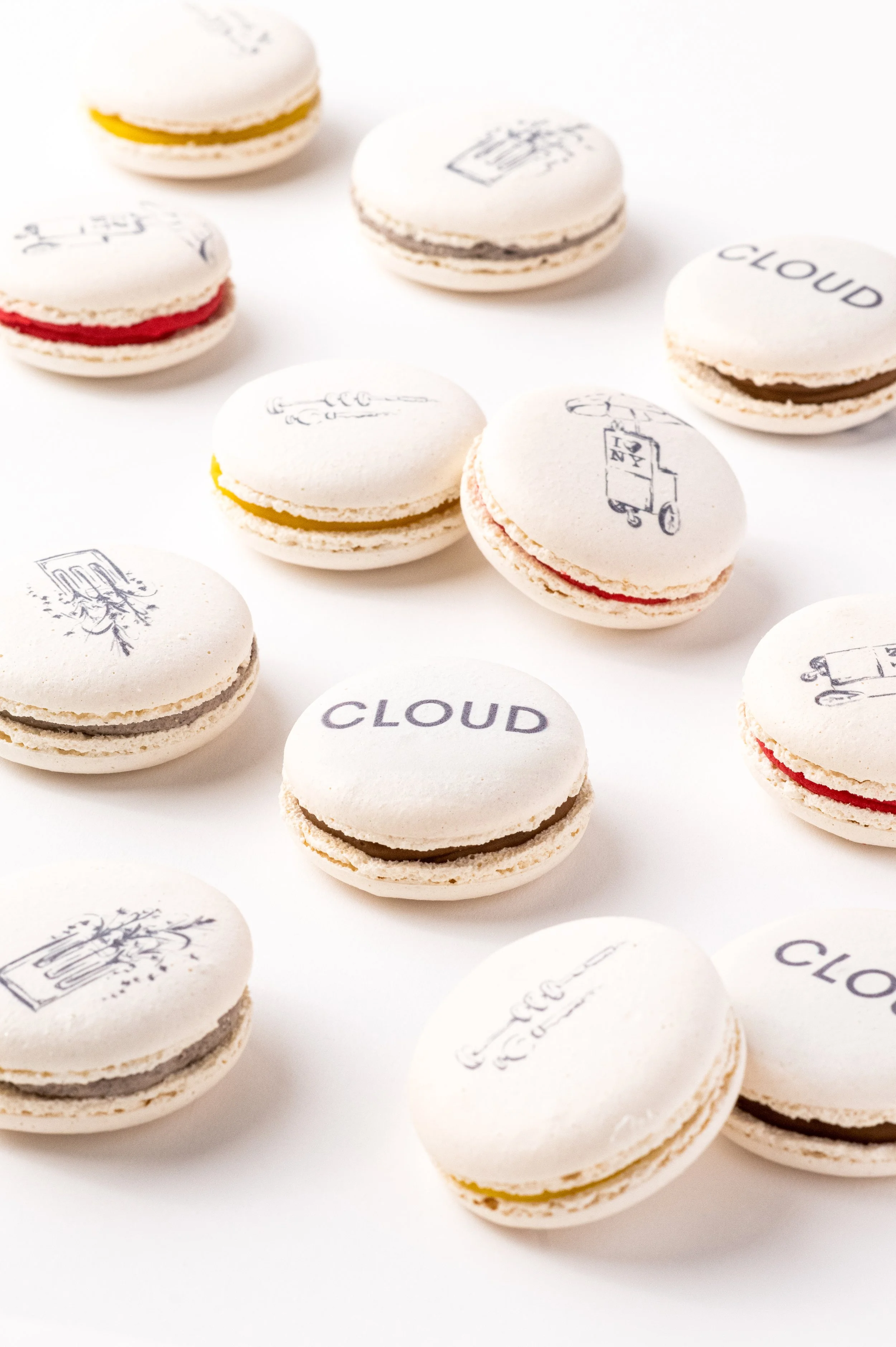 Assorted macarons with white shells and various colored fillings, some with printed or handwritten text on top.