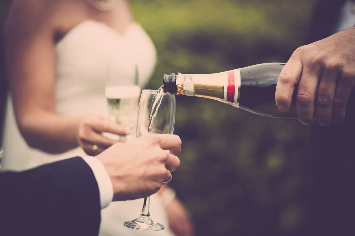 People at a wedding pouring some champaign into some glasses