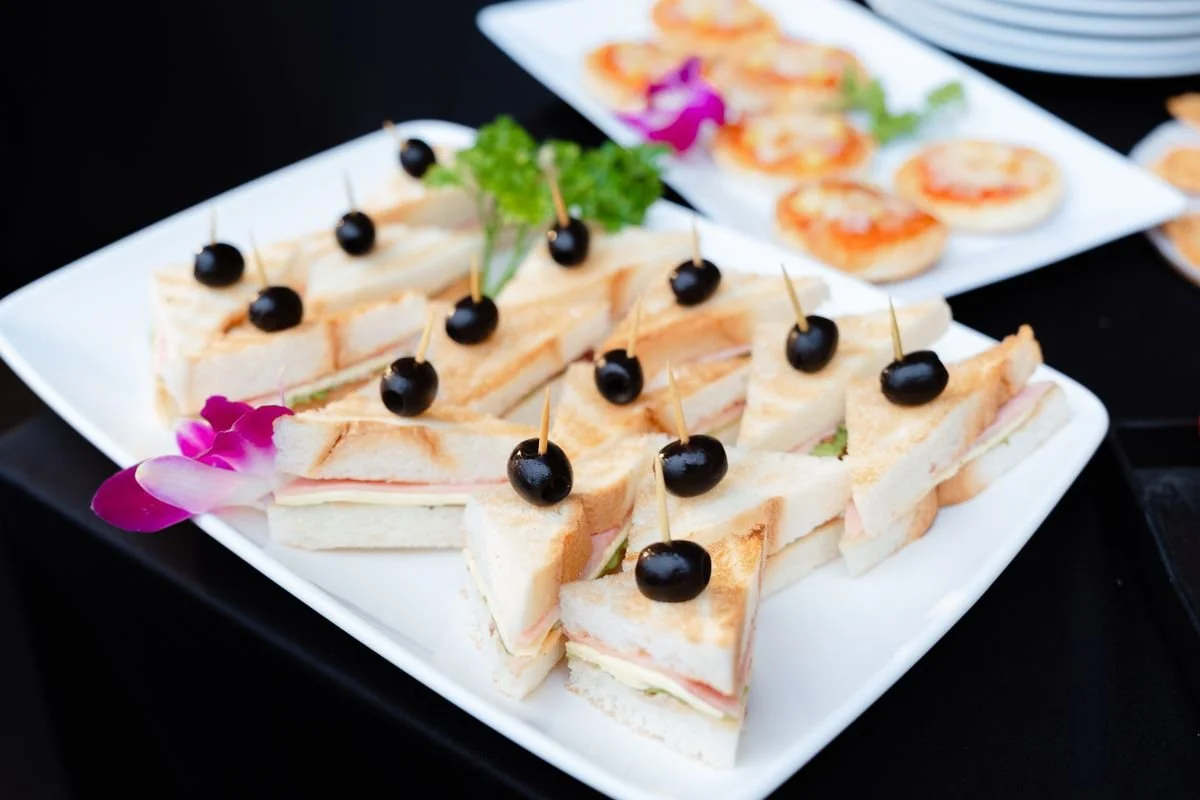 A plate of little sandwiches with olives on top